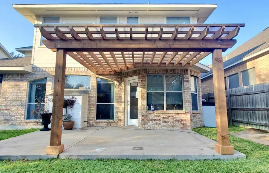 Attached cedar pergola with a clear polycarbonate roof over a bay window