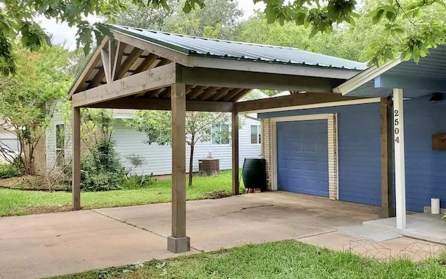 Detached cedar carport with a green R-panel metal roof and dark brown stain