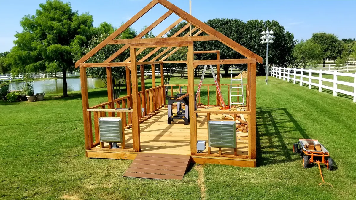 Cedar greenhouse framing with well-draining treated pine flooring and louvered vents during construction