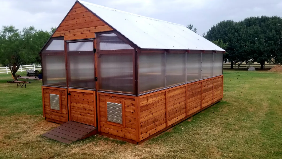 Custom cedar greenhouse with polycarbonate panels and a cedar knee wall