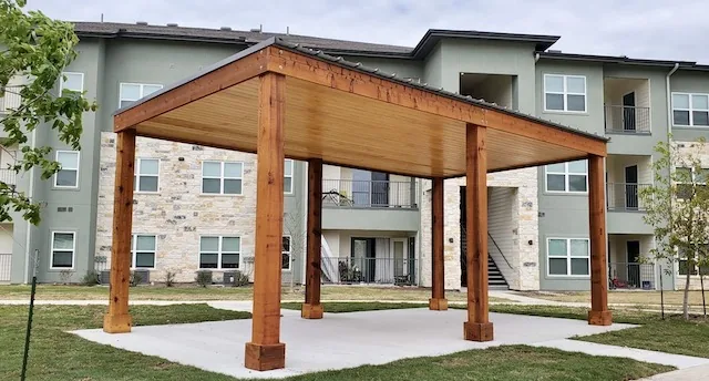 Freestanding flat-roof pavilion with 8x8 cedar posts and a pine tongue-and-groove ceiling at a multifamily property