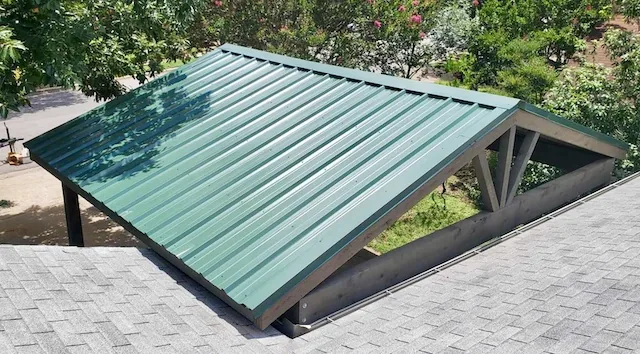 Aerial view of a detached cedar carport with a green R-panel metal roof and dark brown stain